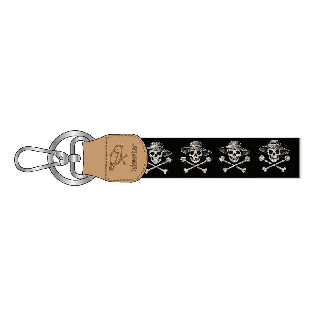 Keychain with skull and crossbones design on a black strap with a brown leather tag featuring a logo.